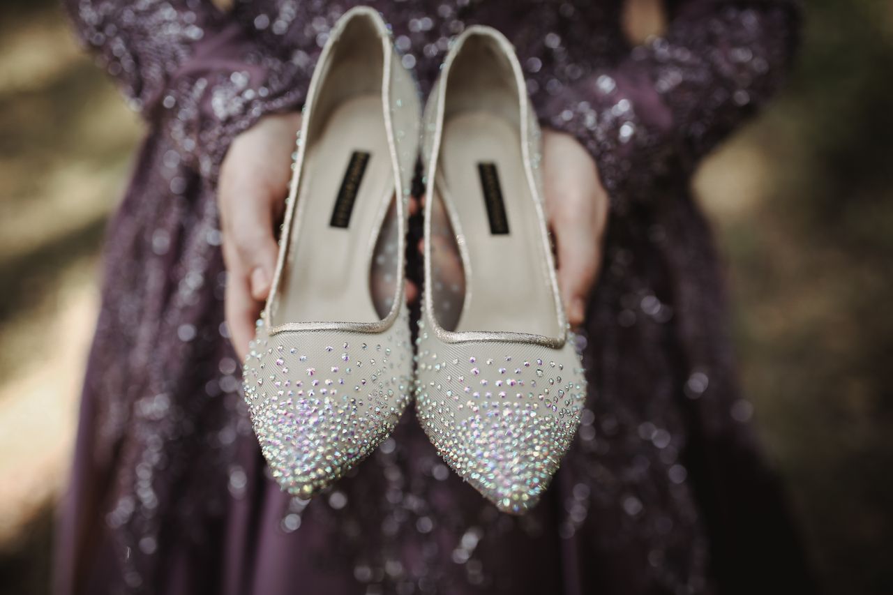 creative-01 Woman in purple sequin dress holding sparkling high heels outdoors.