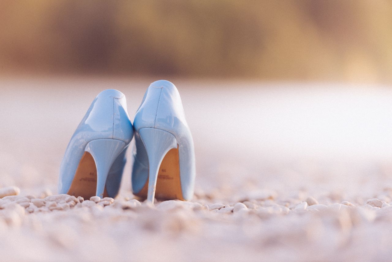 creative-02 Stylish blue high heel shoes photographed on a tranquil pebble beach setting.