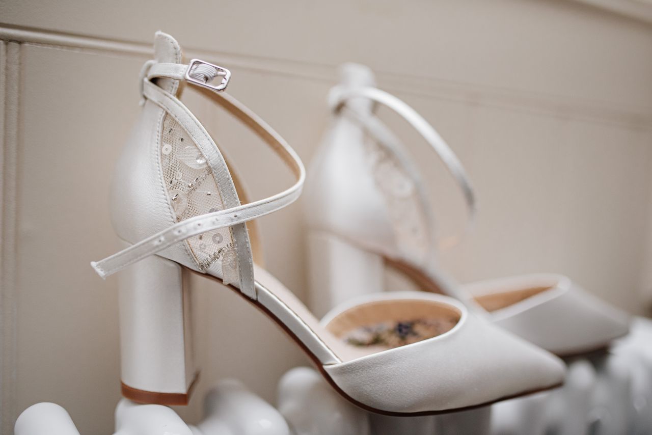 digital-01 Close-up of elegant white bridal heels with lace detail suitable for weddings.