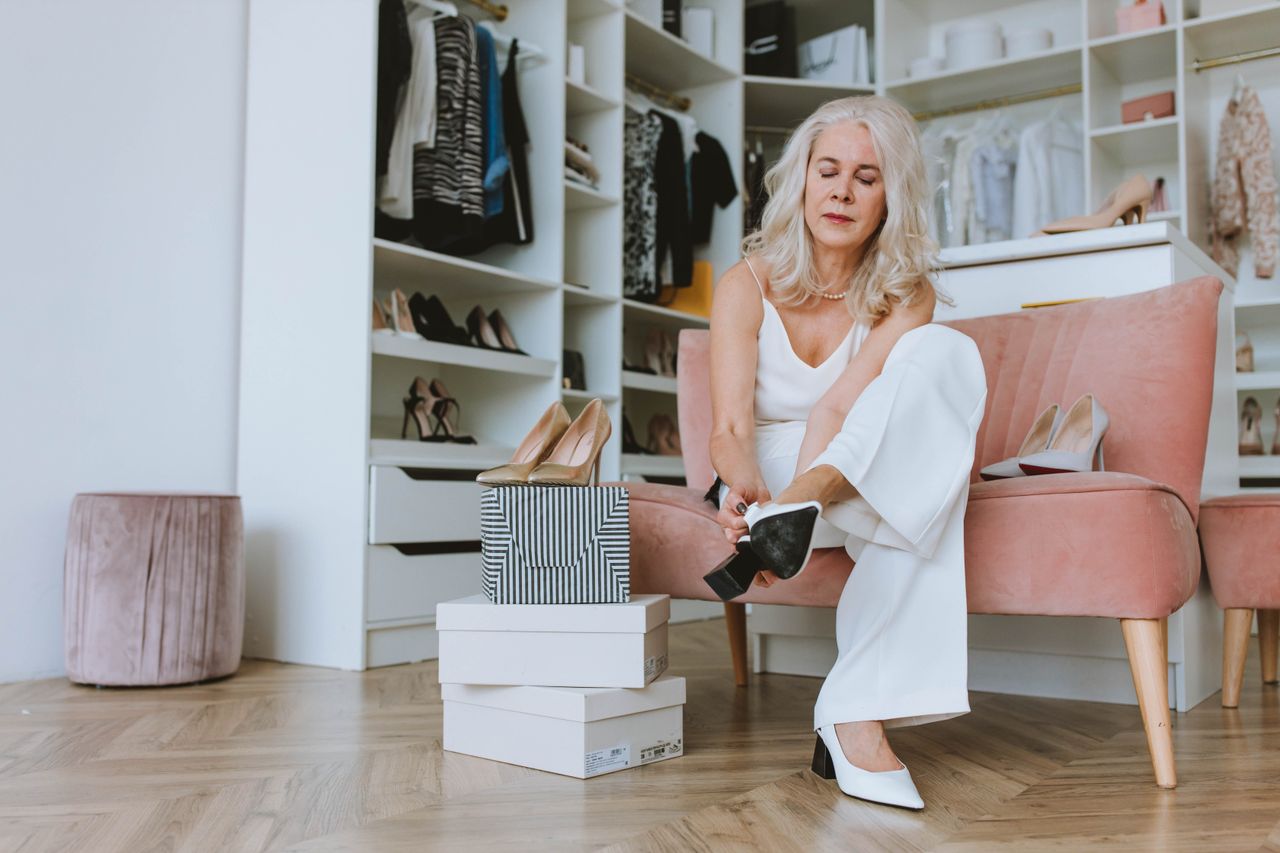 creative-02 Elegant senior woman trying on shoes in a modern walk-in closet setting.